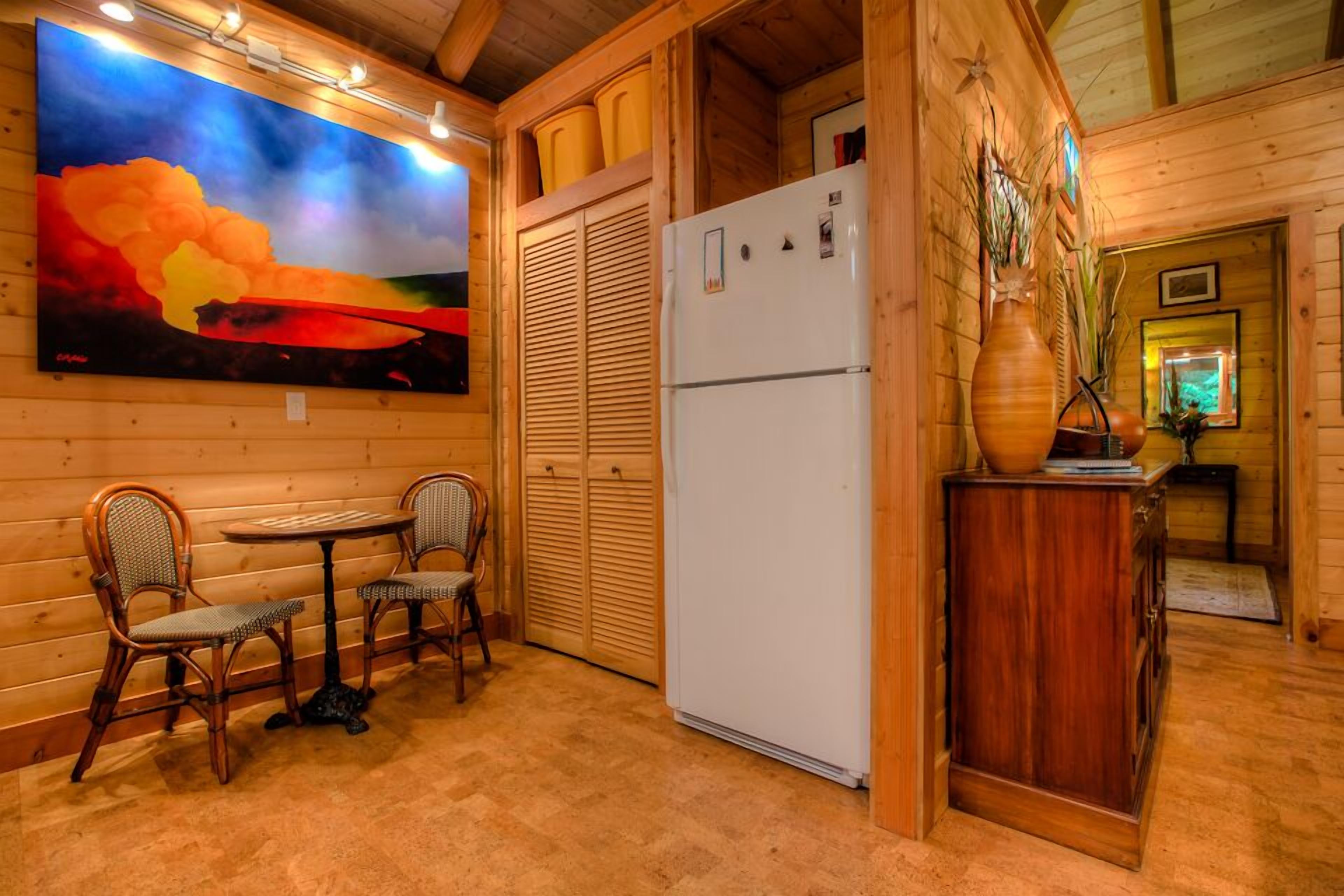 A wooden interior with a dining area, a refrigerator, and a painting on the wall.