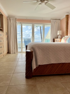 Relax in this serene bedroom with a large bed, nightstand, and wardrobe, offering a tranquil ocean view from the balcony.