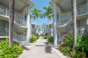 Stroll through the beautifully landscaped corridor, lined with palm trees and lush greenery, leading to balconies.