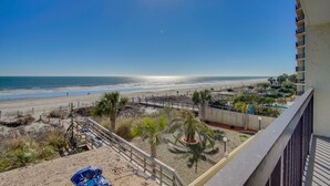 Ein Balkon mit Blick auf einen Strand, einen Pool und ein Gebäude mit Balkonen.