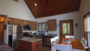 Une cuisine dotée de meubles en bois, d’un réfrigérateur, d’un four à micro-ondes et d’un coin repas avec une table et des chaises.