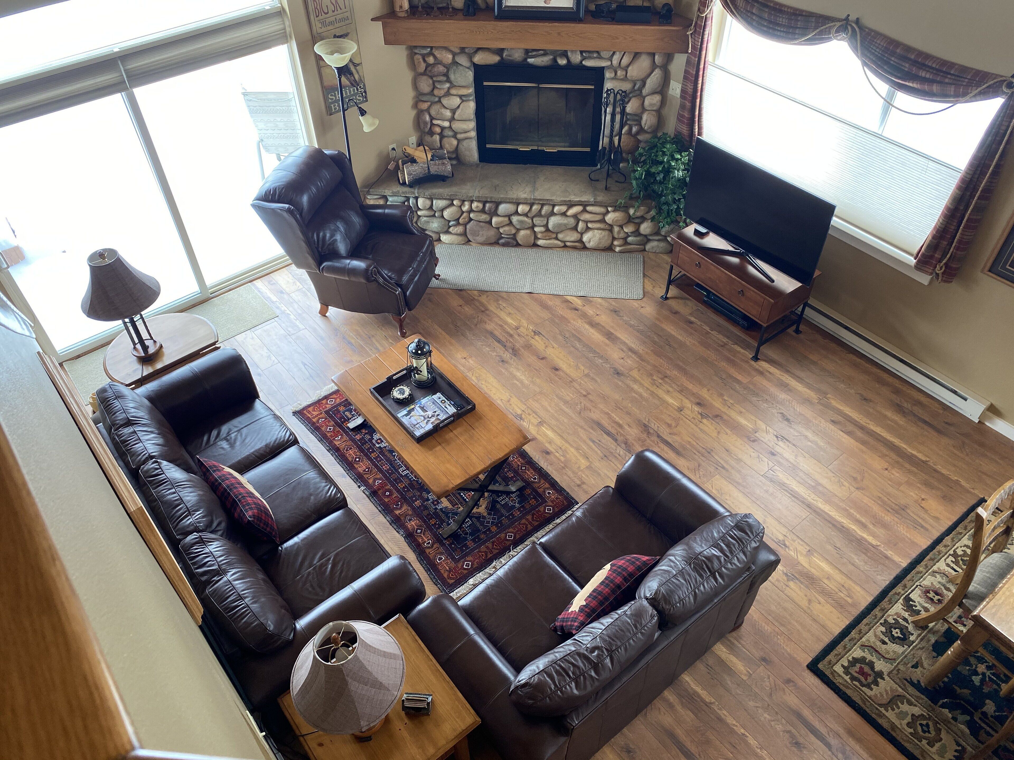 A living room with a stone fireplace, leather sofas, a coffee table, and a television.