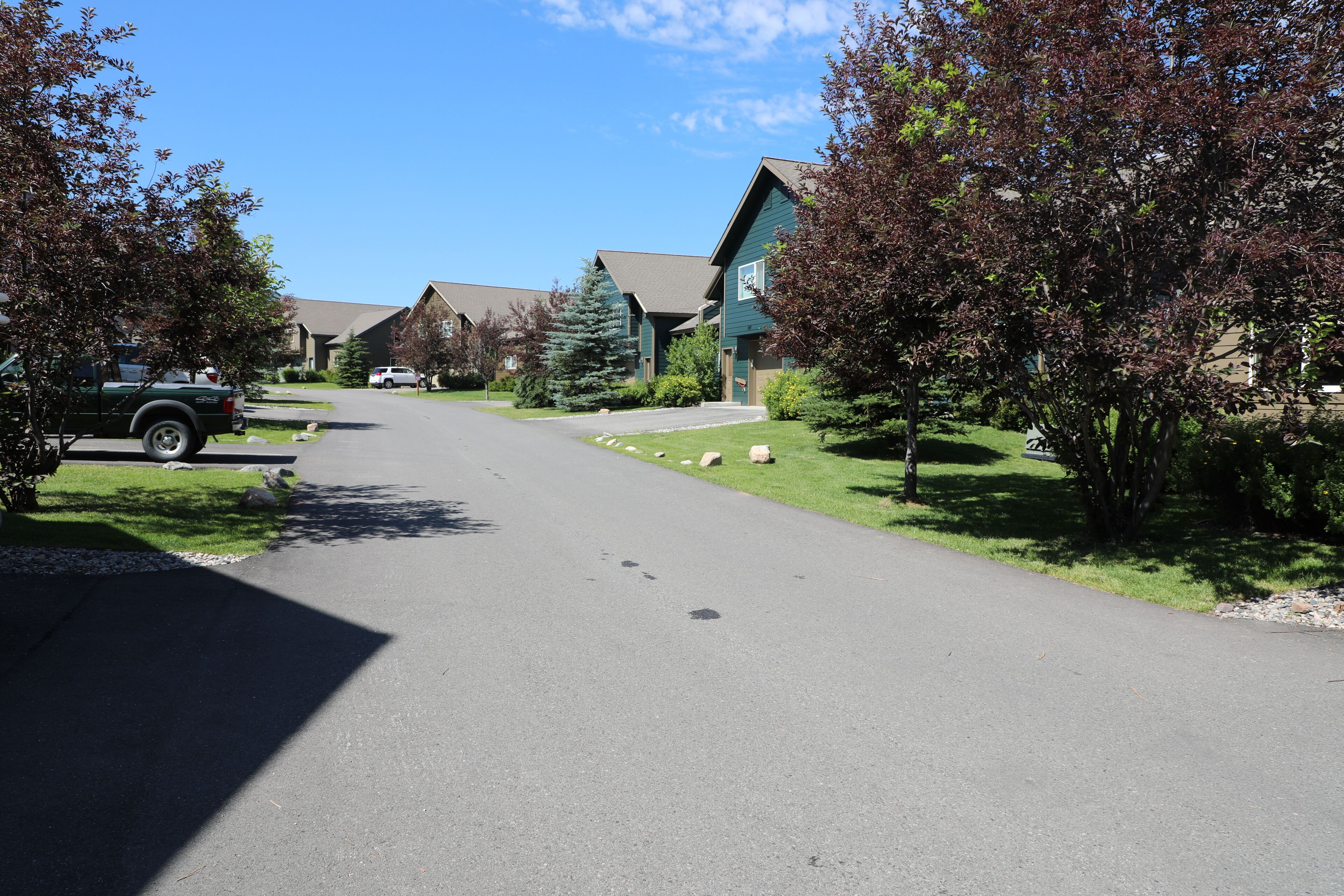 A residential street with houses, a parked truck, and a clear sky.