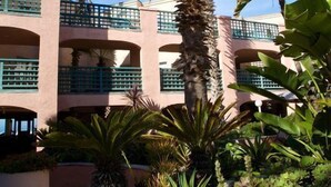 A multi-story building with balconies, surrounded by lush tropical plants.