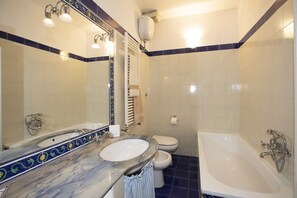A bathroom with a marble sink, a bathtub, and a toilet.