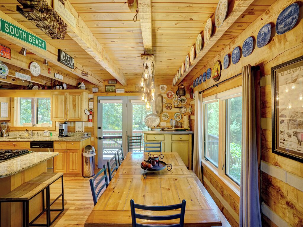 A wooden cabin kitchen with a central island, wooden cabinets, and a dining table.