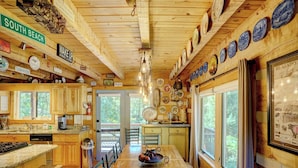 Una cucina in baita di legno con isola centrale, mobili in legno e un tavolo da pranzo.