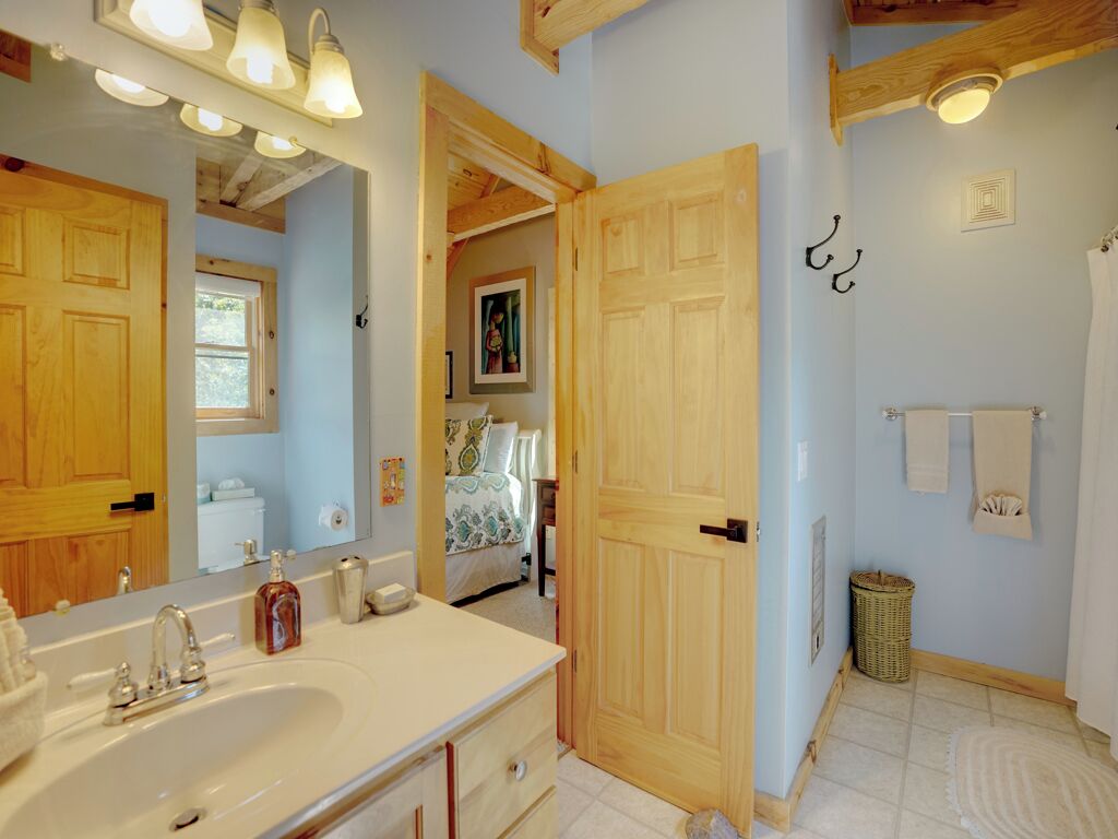 Un baño con un lavamanos grande, una puerta de madera y un espejo.