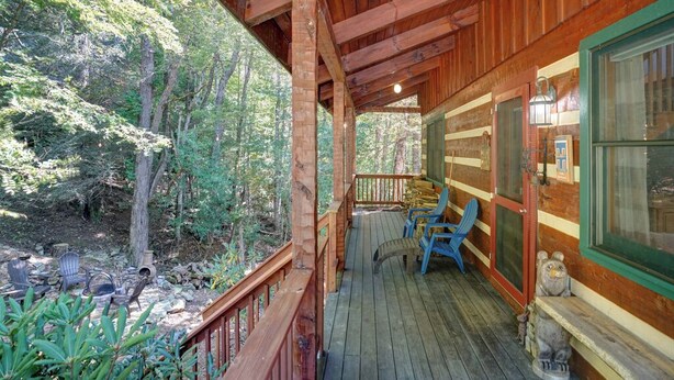 Una baita di legno con veranda, posti a sedere all'aperto e vista sulla foresta.