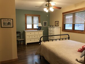 A bedroom with a bed, a dresser, a chair, and a ceiling fan. - Cottage on Lake Bellaire July and Aug Openings (Bellaire)