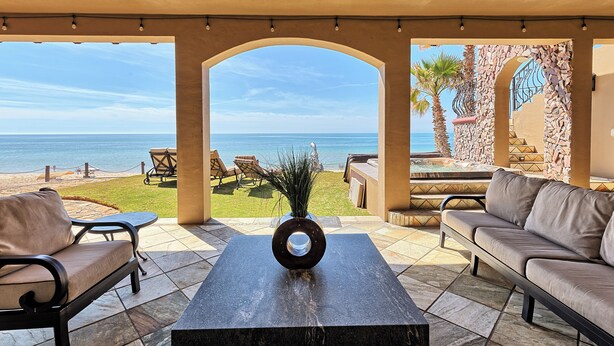 Una veranda riparata con vista sul mare, arredi da esterno e un vaso decorativo.