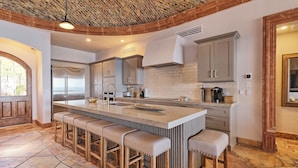 Una cucina moderna con isola centrale, sgabelli da bar e un soffitto rustico.
