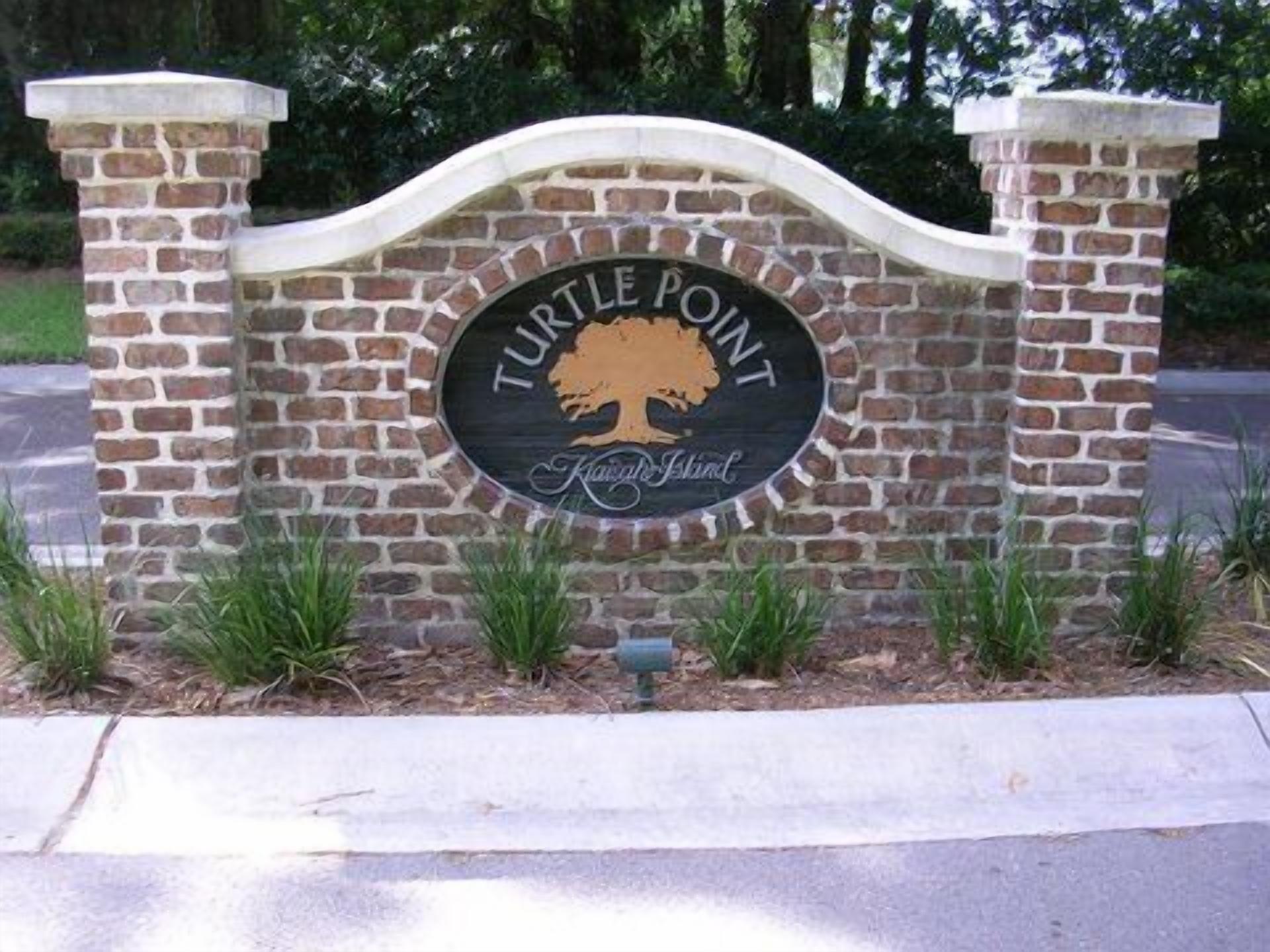 A sign with "Turtle Point" and "Family Island" text, surrounded by brick pillars and greenery.