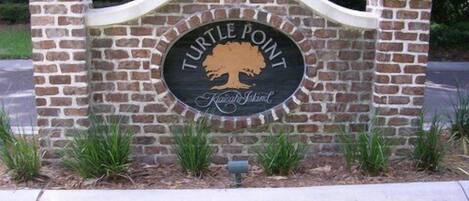 A sign with "Turtle Point" and "Family Island" text, surrounded by brick pillars and greenery.