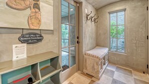 A hallway with a bench, a shoe artwork, a 'Please Remove Your Shoes' sign, and a radiator.