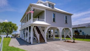 A two-story house with a porch, a staircase, and an American flag. - Vacation Paradise! Awesome Waterfront Home, Unbelievable View Of Stump Sound! (Surf City)