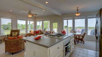 A spacious kitchen with a central island, large windows, and a view of the outdoors.