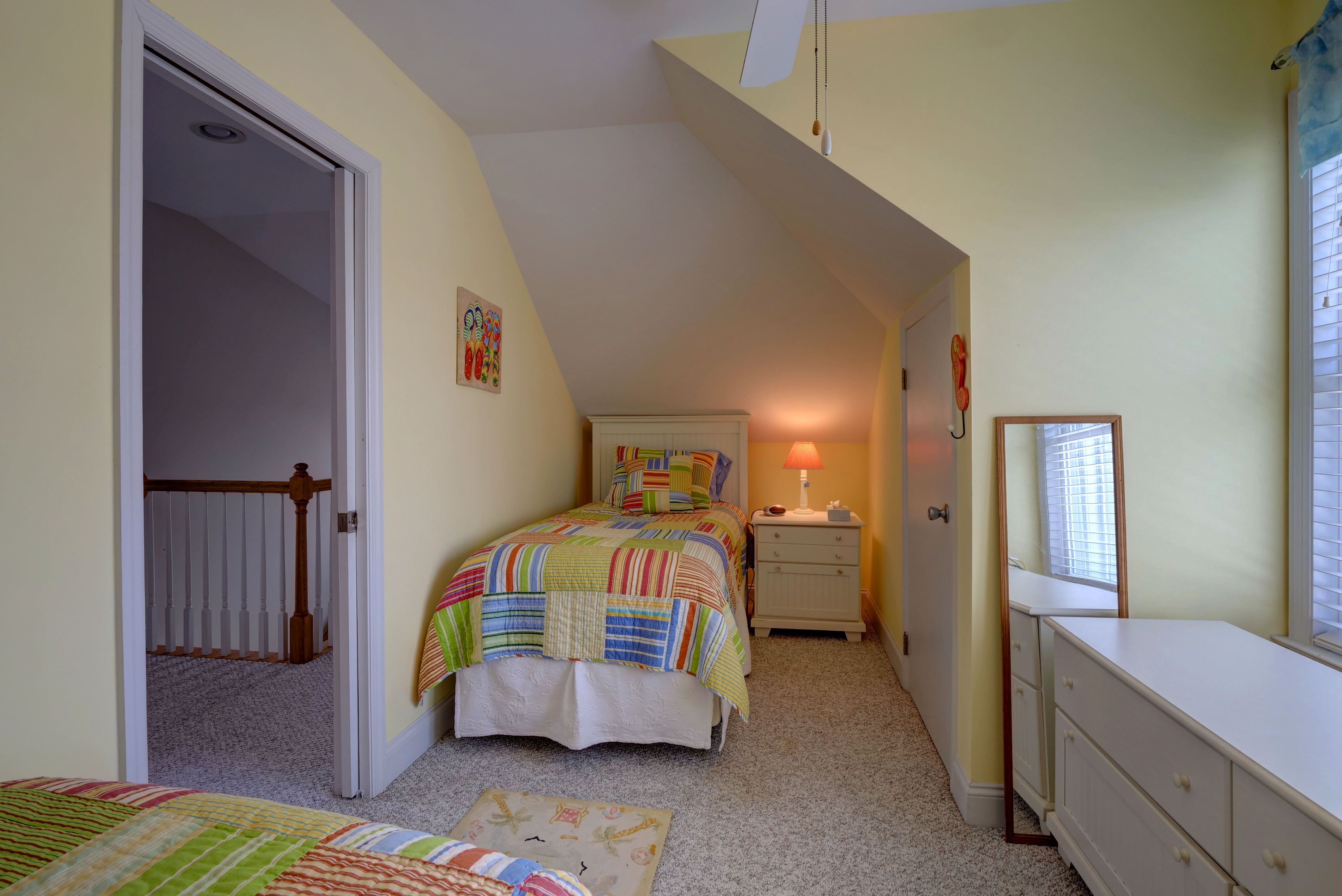 Ein Schlafzimmer mit Bett, Nachttisch, Schminktisch und einem Fenster mit Jalousien.