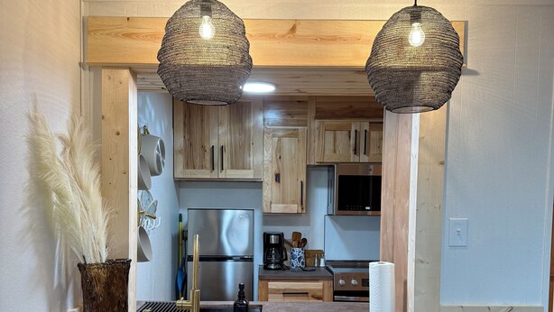 Una cocina con armarios de madera, una isla central con taburetes de bar y dos lámparas colgantes.