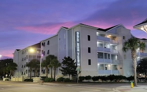 A multi-story hotel with a prominent vertical sign, balconies, and a street view.