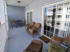 A covered patio with wicker furniture, a sliding glass door, and a small table. - MBV 6Br/5Ba - 302B (Myrtle Beach)