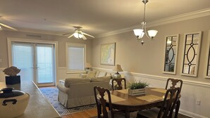 A dining area with a wooden table and chairs, a ceiling fan, and a chandelier. - Luxury 3BR 2.5 B Condo Just Steps from the Ocean! (Tybee Island)