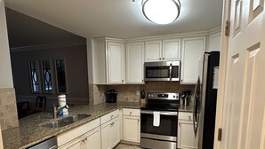 A kitchen with white cabinets, a stainless steel refrigerator, a microwave, an oven, and a dishwasher. - Luxury 3BR 2.5 B Condo Just Steps from the Ocean! (Tybee Island)