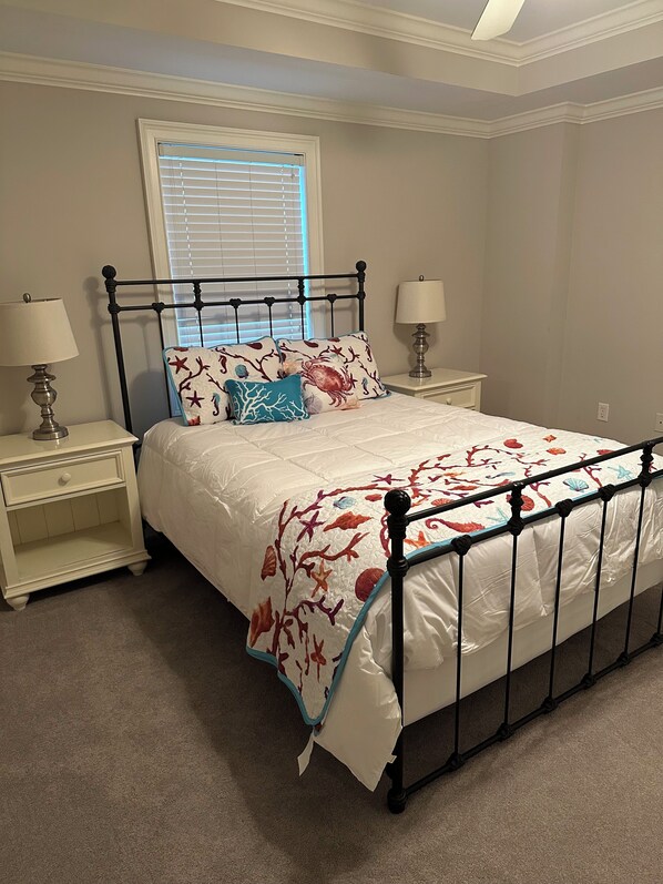 A neatly arranged bedroom with a bed, two bedside tables, and a window with blinds.