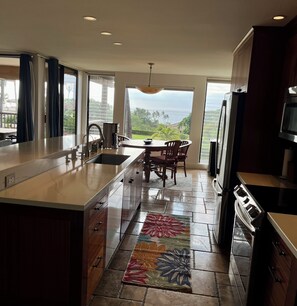 Una cocina con una isla grande, una zona de comedor con vistas y un refrigerador.
