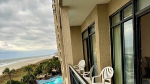 A balcony with a pool, lounge chairs, and a view of the beach. - Gorgeous direct oceanfront- end unit in highly desirable location! 
 (North Myrtle Beach)