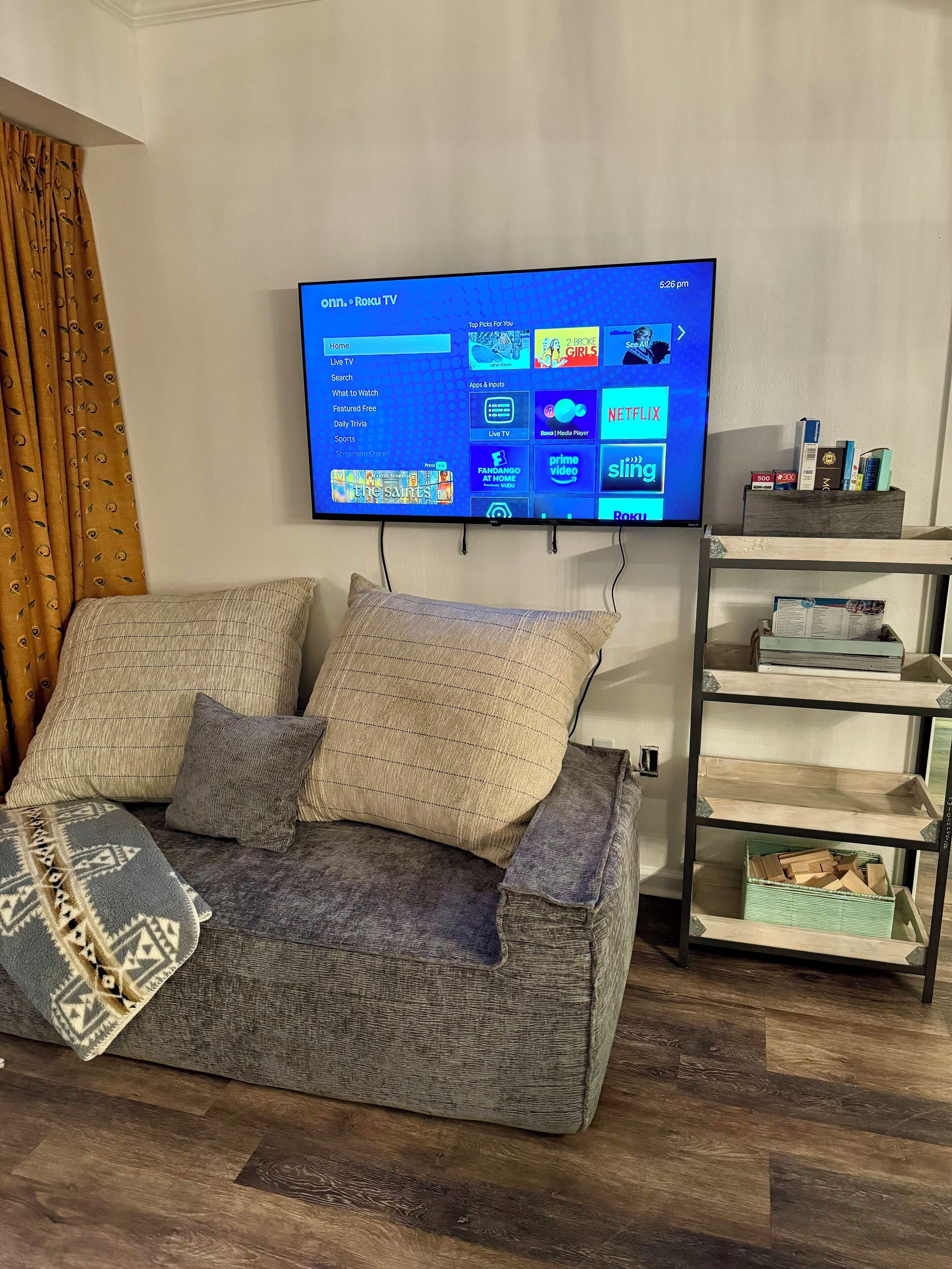 Ett vardagsrum med en platt-TV som är monterad på väggen och som visar gränssnittet för en streamingtjänst.