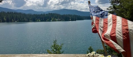 A lake with mountains in the background and an American flag on a railing.