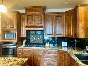 A kitchen with wooden cabinets, stainless steel appliances, and a granite countertop. - Family-friendly Lakefront Home w/Kayaks, Paddleboards & More-Close to Silverwood (Hayden)