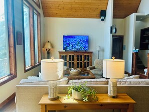 A living room with a sofa, two lamps, a television, and a cabinet. - Family-friendly Lakefront Home w/Kayaks, Paddleboards & More-Close to Silverwood (Hayden)