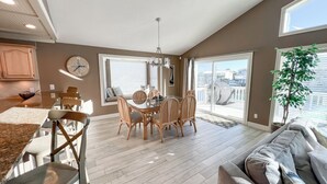 Un vaste espace de vie comprenant une table à manger, des chaises, un canapé et une grande fenêtre donnant sur l’extérieur.