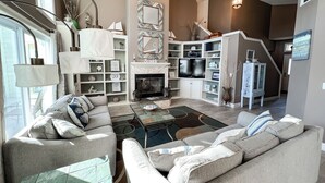Un salon spacieux doté d’une cheminée, d’un téléviseur et d’un ventilateur de plafond.