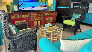 Ein Wohnzimmer mit Fernseher, Rattanmöbeln, einer Couch und einem Etagenbett.