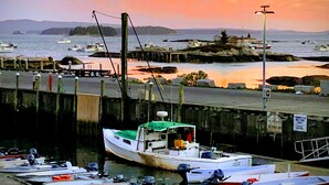 A marina with boats docked, a pier extending into the water, and a sunset in the background. - Renovated 1854 Sea Captain's House w/Harbor Views in Deer Isle Village (Deer isle)