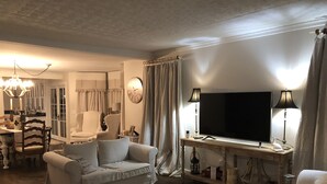 A living room with a sofa, a television, a table with a lamp, and a clock on the wall. - Renovated 1854 Sea Captain's House w/Harbor Views in Deer Isle Village (Deer isle)