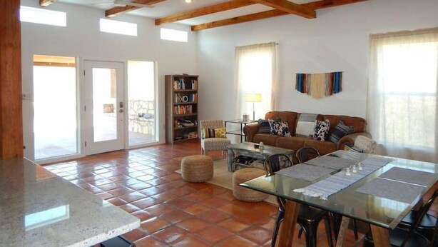 Un vaste espace de vie doté d’un sol carrelé, d’une table à manger en verre, d’un ensemble de canapés et d’une bibliothèque.