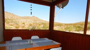 Une table en bois offrant une vue sur un paysage désertique grâce à de grandes fenêtres.