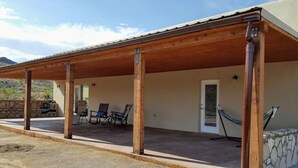 Un espace extérieur abrité, doté d’un mur en pierre, de piliers en bois et d’une porte.
