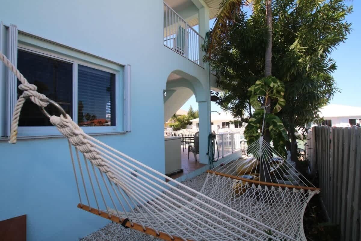 Un hamac est suspendu entre deux immeubles, une fenêtre et un arbre.