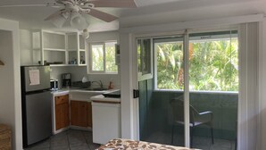 A compact kitchen with a refrigerator, microwave, and sink, and a balcony with a view of greenery. - 1 Mile from Pipeline Surf Break! (Haleiwa)