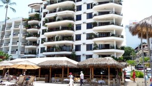 A multi-story hotel with balconies, outdoor seating, and a beachside location.