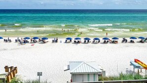 A beach with white sand, clear blue water, and a row of blue umbrellas. - NEWLY TOTALLY RENOVATED   5⭐️STAR sleeps 8  (Panama City Beach)