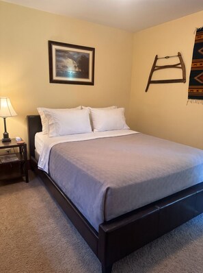 A single bed with a headboard, a bedside table with a lamp, and a framed picture on the wall.