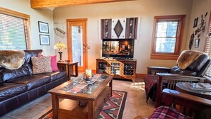 Ein geräumiges Wohnzimmer mit hoher Decke, Kamin, Fernseher und einer gemütlichen Sitzecke.