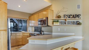 Una cocina moderna con armarios de madera, un microondas de acero inoxidable y una encimera blanca.