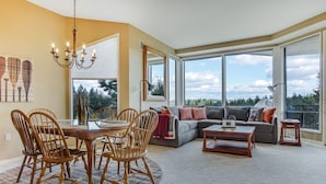 Un salón espacioso con comedor, ventanas amplias y vistas al exterior.